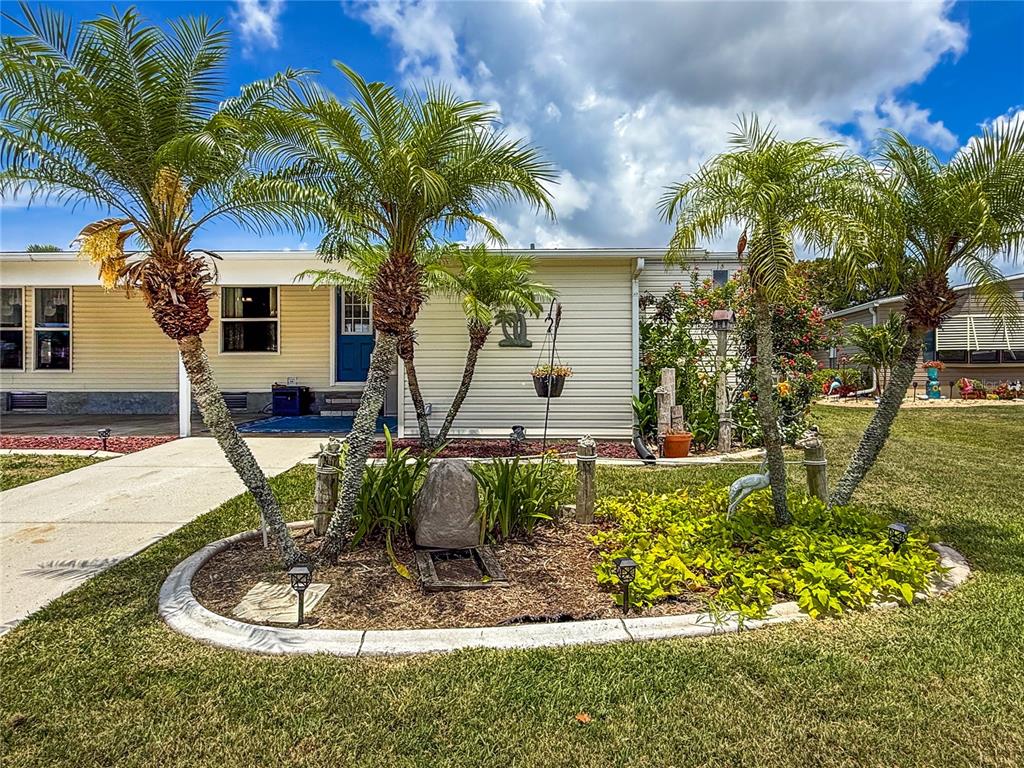 A single-story house with palm trees and a landscaped garden in the front yard — 73 WHIPPORWILL COURT, ELLENTON, FL