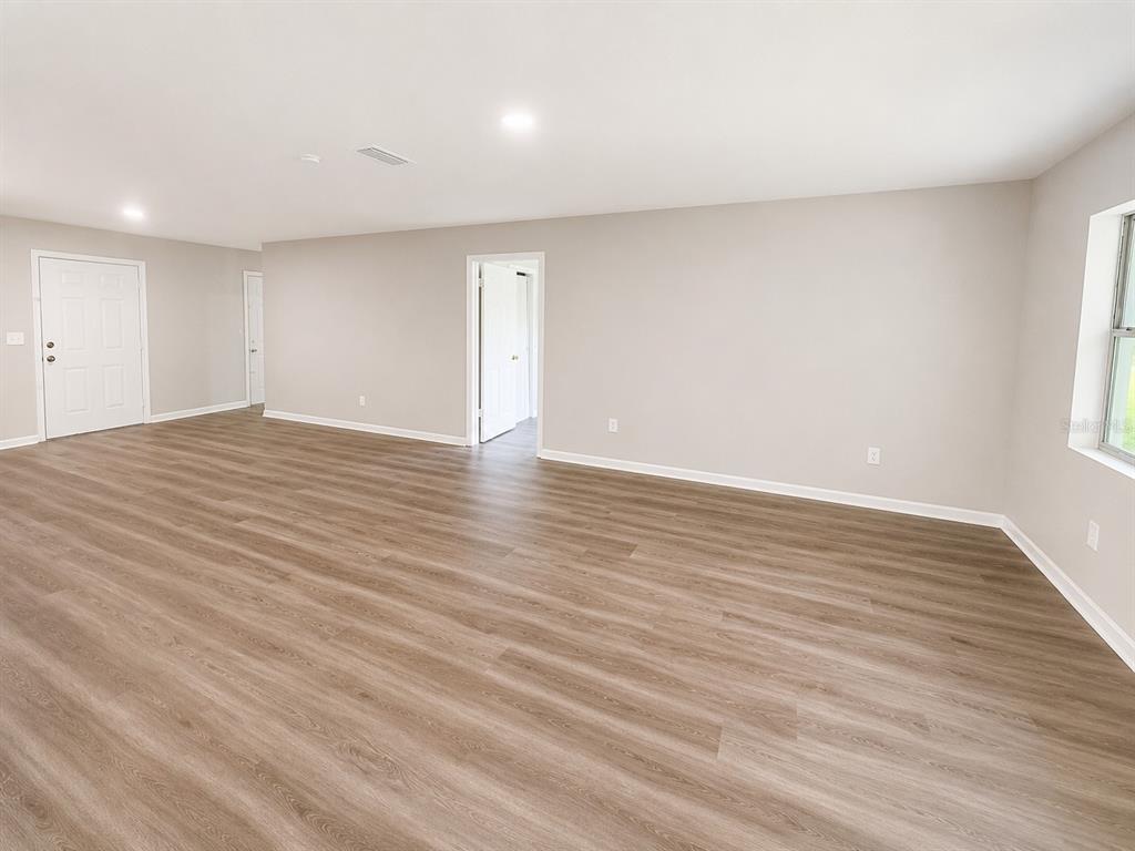 An empty room with light gray walls, wood-look flooring, and a white doorway — 21450 NE 35TH STREET, WILLISTON, FL