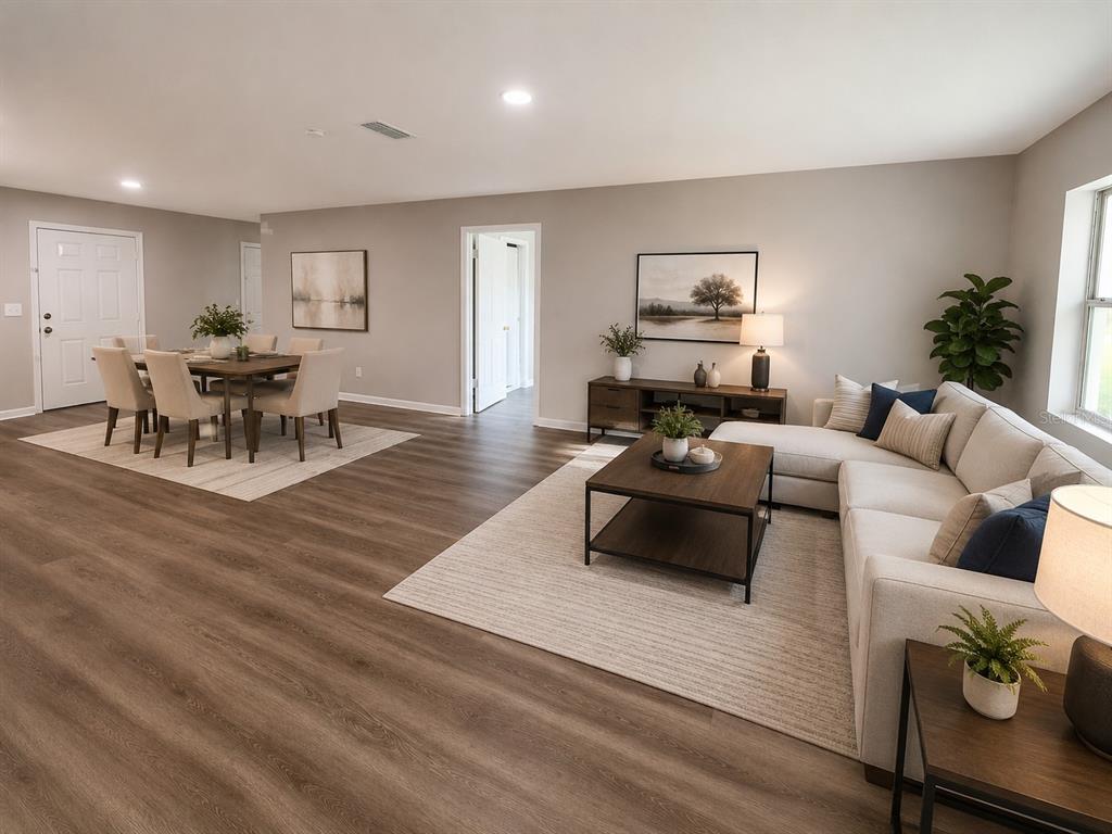 An open-concept living and dining area features wood-look flooring, neutral walls, and modern furniture — 21450 NE 35TH STREET, WILLISTON, FL