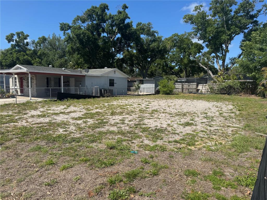 A large, mostly dirt and grass vacant lot sits next to a single-story house — 6803 S CORTEZ STREET, TAMPA, FL
