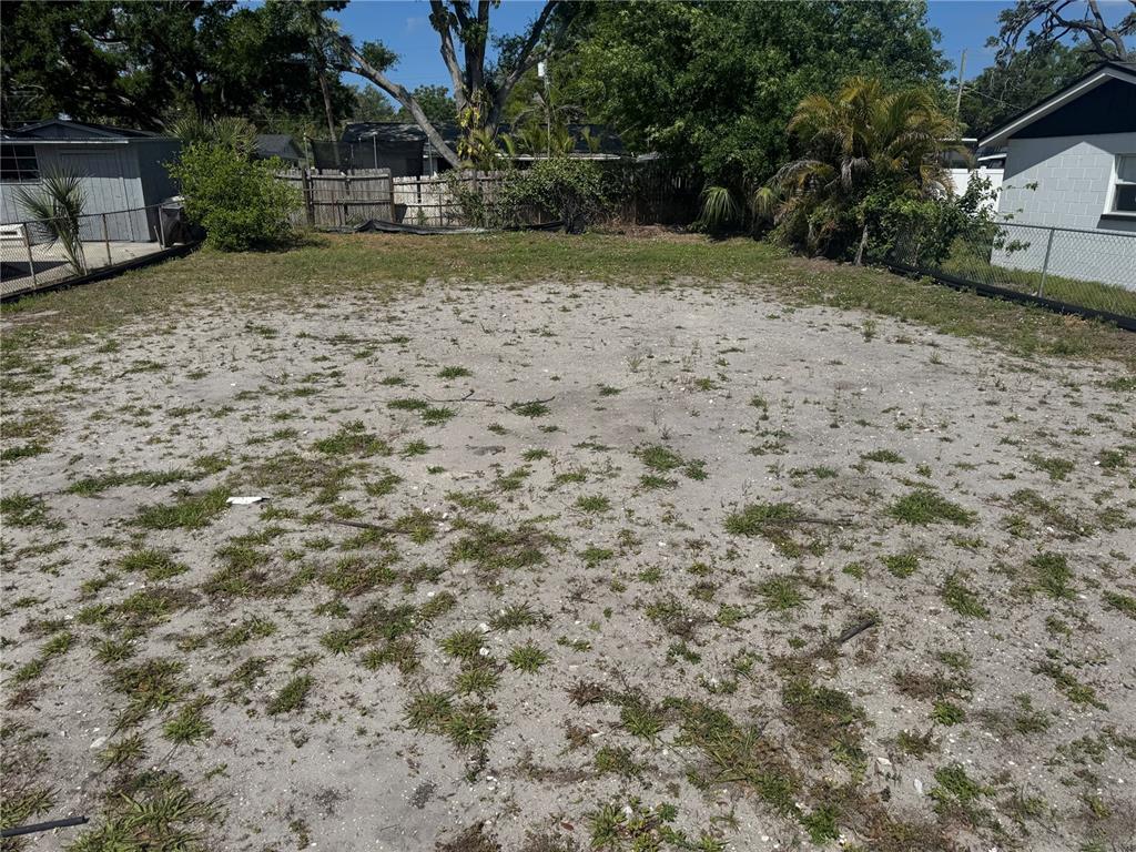 A flat, sandy residential lot with sparse grass and surrounding fences and trees — 6803 S CORTEZ STREET, TAMPA, FL