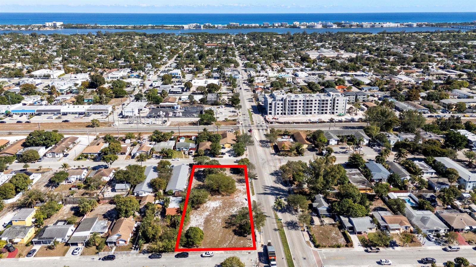 An aerial view shows a vacant rectangular lot outlined in red along a city street — 1212 10th Avenue N, FL 33460, FL