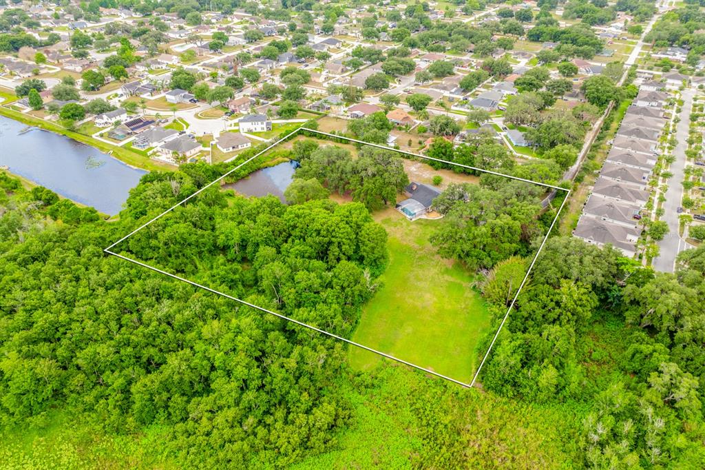 An aerial view shows a house with a pool on a large, partially wooded lot — 1600 E 10TH STREET, ST CLOUD, FL