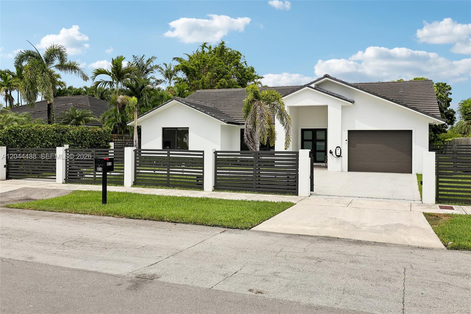 A single-story white house features a dark tiled roof, horizontal slat fencing, and a driveway — 6816 SW 89th Ct, Miami FL 33173, MIAMI, FL