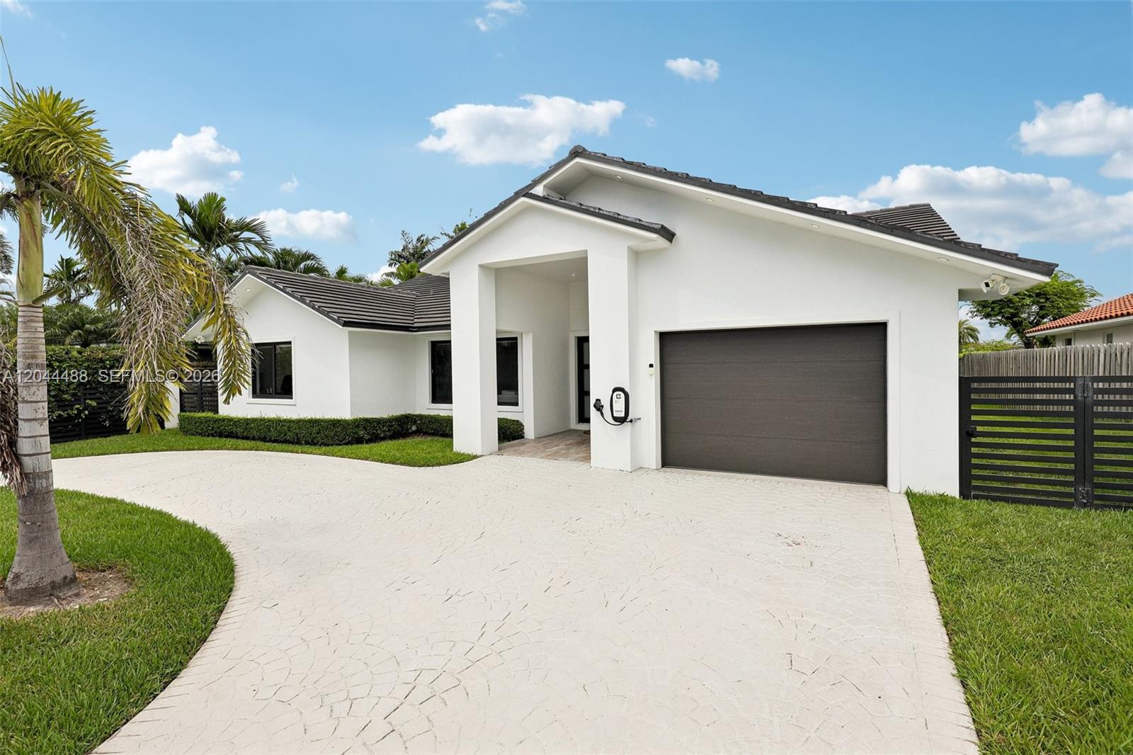 A white single-story house with a dark garage door, paved driveway, and palm tree — 6816 SW 89th Ct, Miami FL 33173, MIAMI, FL