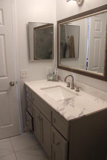 A bathroom vanity features a marble countertop, a rectangular sink, and a framed wall mirror — 1803 Waterview Circle, Palm Springs FL 33461, PALM SPRINGS, FL