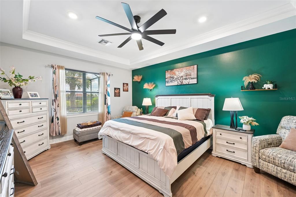 A bedroom features a green accent wall, a white bed frame, and wood-look flooring — 13356 VERANDI STREET, VENICE, FL