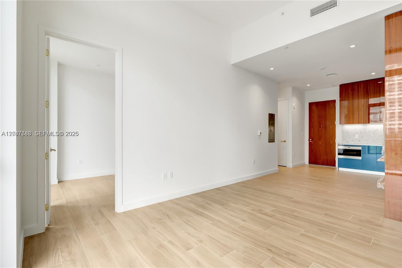 This interior view shows a living area with light wood floors, white walls, and a kitchen — 2655 S Bayshore Dr # 403, Miami FL 33133, MIAMI, FL