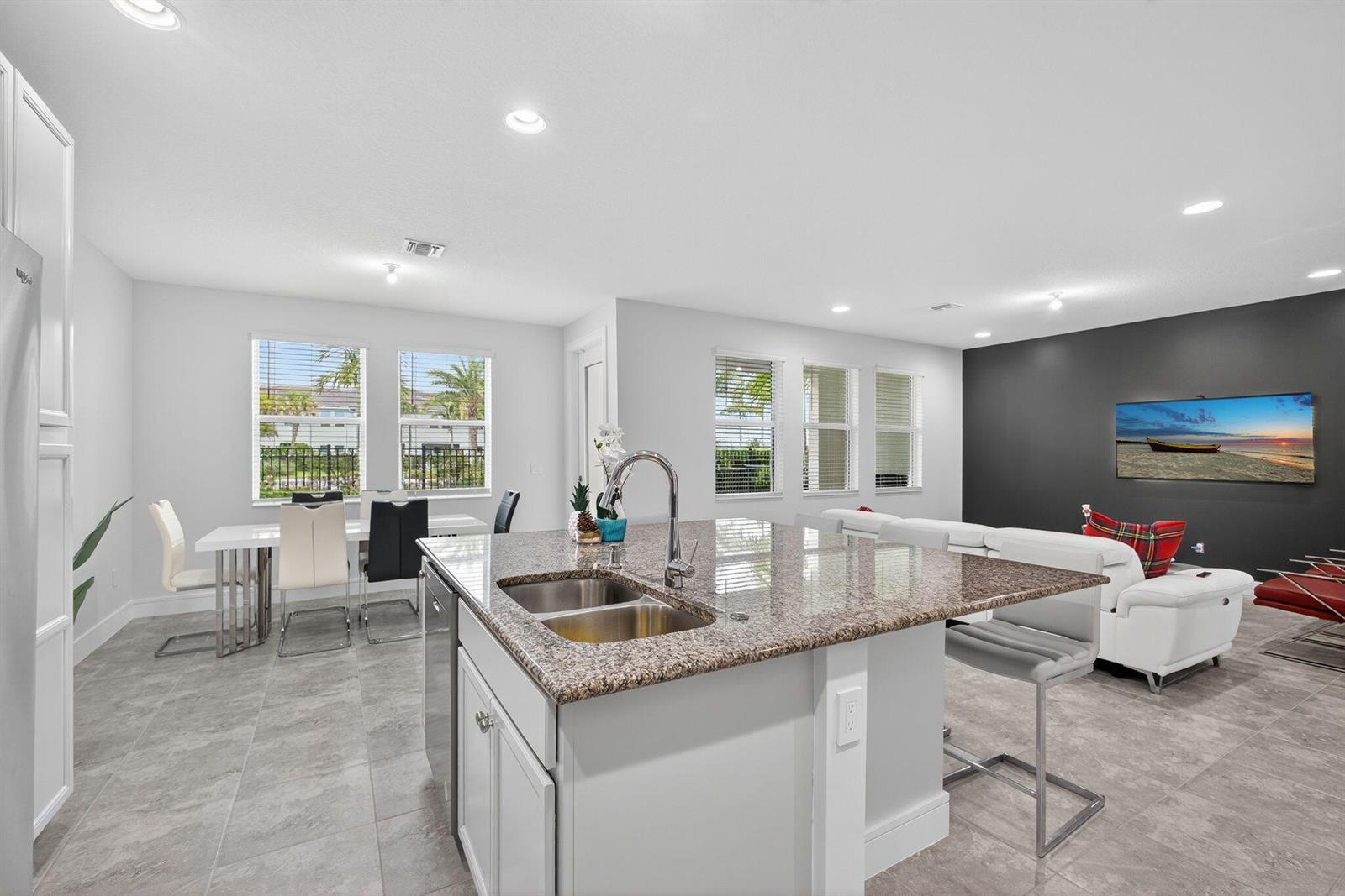 A modern kitchen with a granite island, stainless sink, and open-concept living area — 16131 Oakview Drive, Westlake FL 33470, WESTLAKE, FL