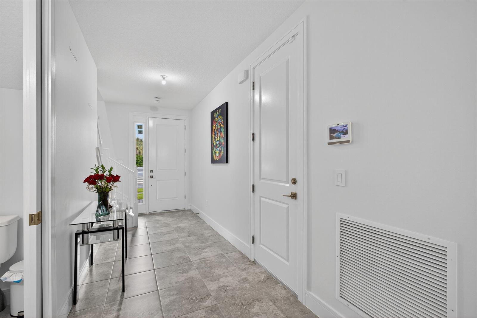 A tiled entryway features a glass console table, white doors, and a wall-mounted security panel — 16131 Oakview Drive, Westlake FL 33470, WESTLAKE, FL