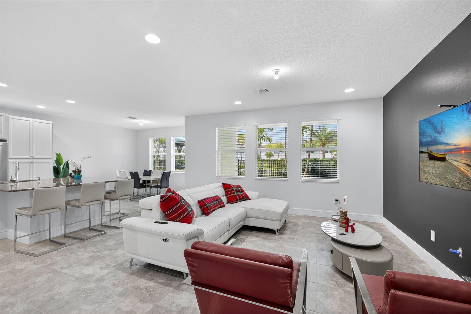 A modern living room features a white sectional, red chairs, and a wall-mounted television — 16131 Oakview Drive, Westlake FL 33470, WESTLAKE, FL