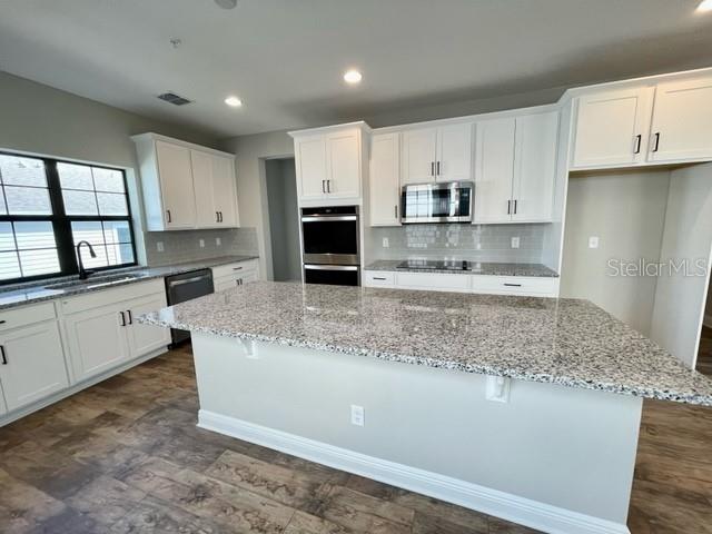 A modern kitchen features white cabinets, granite countertops, a large island, and stainless steel appliances — 1120 SPOTTED SANDPIPER LOOP, WINTER SPRINGS, FL