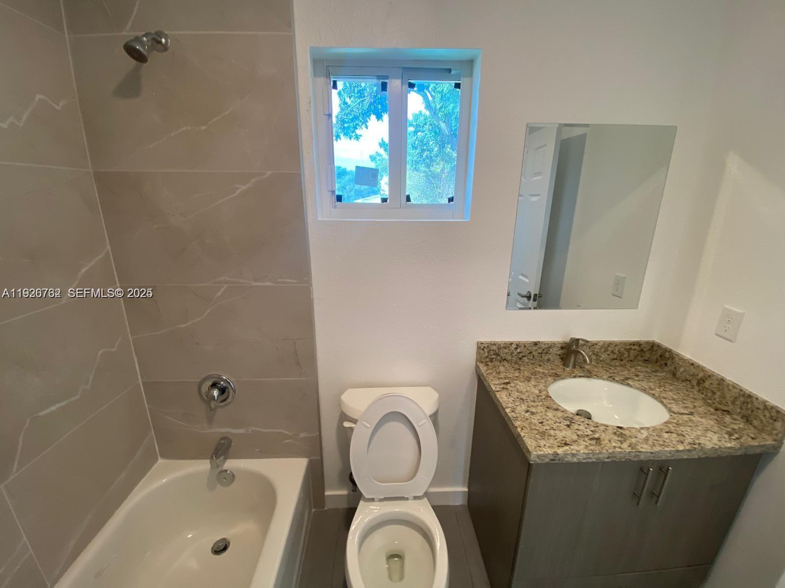 A bathroom features a tiled shower-tub combination, a toilet, and a granite-topped vanity — 1783 NW 65th St # 1783, Miami FL 33147, MIAMI, FL