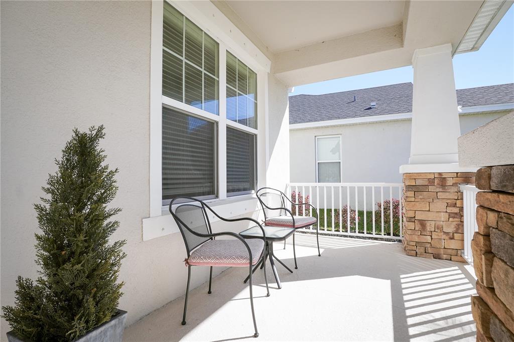 A covered porch features a concrete floor, two metal chairs, and a stone-based pillar — 6332 LAURELCREST GLEN, PALMETTO, FL