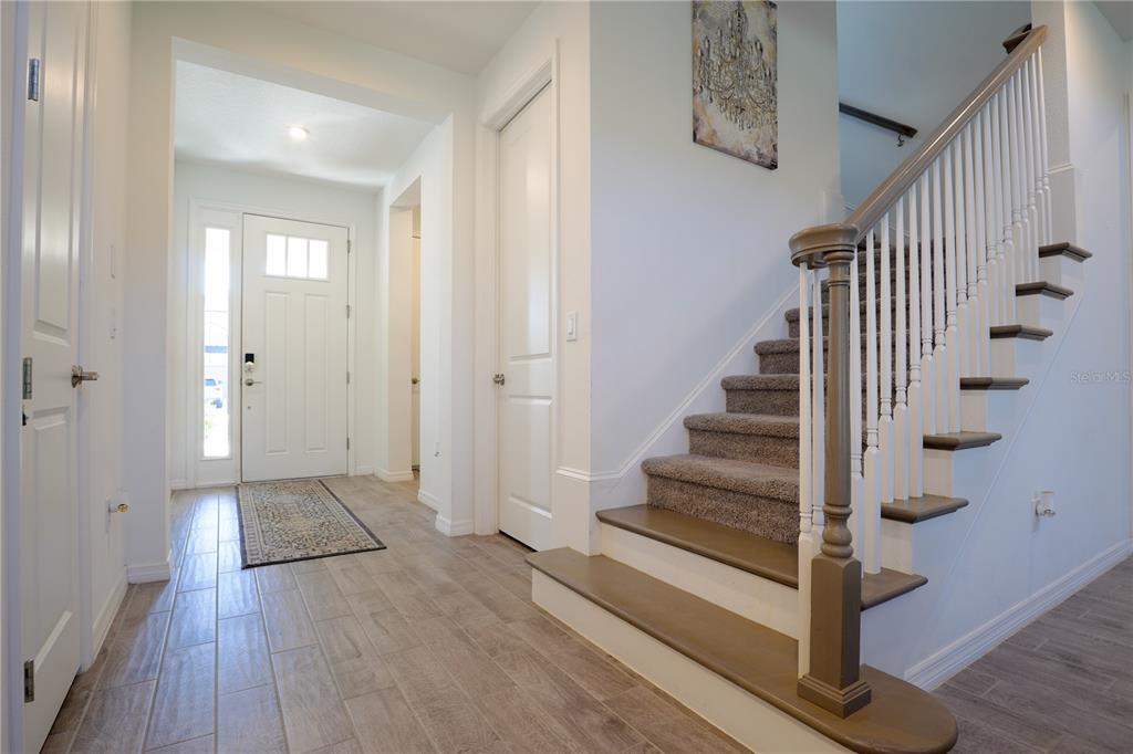 A foyer features wood-look tile flooring, a white front door, and a carpeted staircase — 6332 LAURELCREST GLEN, PALMETTO, FL