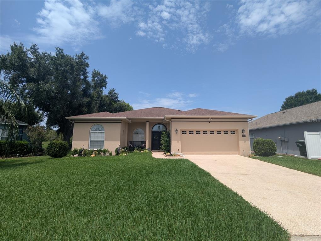 A single-story house with a tan exterior, a two-car garage, and a concrete driveway — 3914 DERBY DRIVE, LAKELAND, FL
