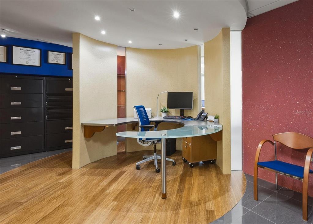 A modern office space features a curved desk, wood flooring, and a blue accent wall — 501 PERSEO ST STE 208, CAPARRA HILLS, PR