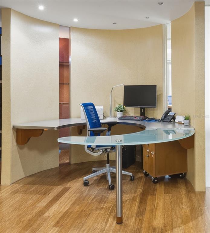 A curved office desk with a glass top sits in a room with wood flooring — 501 PERSEO ST STE 208, CAPARRA HILLS, PR