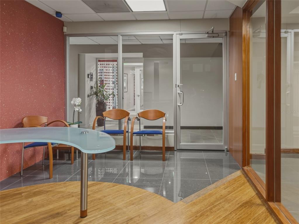 A waiting area features a glass desk, blue chairs, tile flooring, and a glass door — 501 PERSEO ST STE 208, CAPARRA HILLS, PR