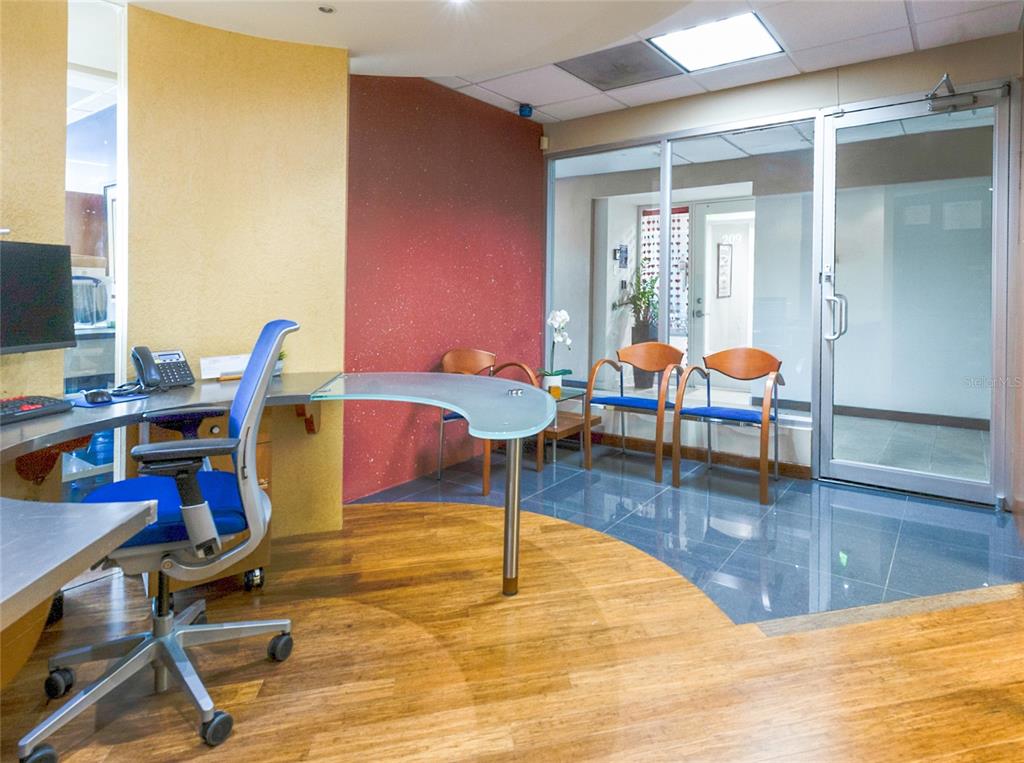 A reception area features a curved glass desk, blue office chair, and a waiting area — 501 PERSEO ST STE 208, CAPARRA HILLS, PR