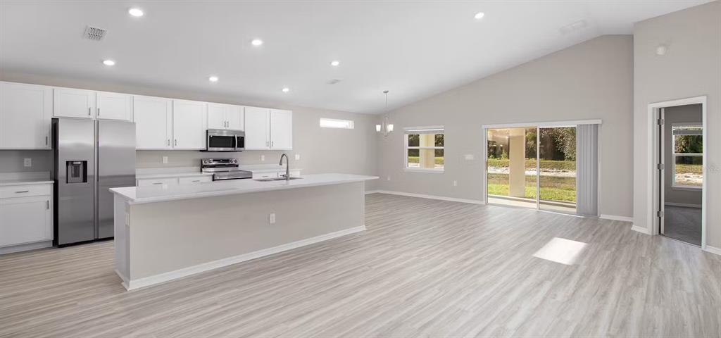 A modern kitchen with white cabinets, stainless steel appliances, and a large island — 6873 SUNDIAL DRIVE, LAKELAND, FL