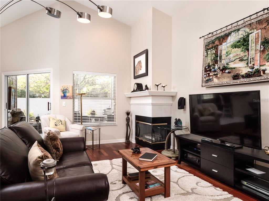 A living room features a dark leather sofa, a fireplace, and a large television — 6126 NW 36TH DRIVE, GAINESVILLE, FL