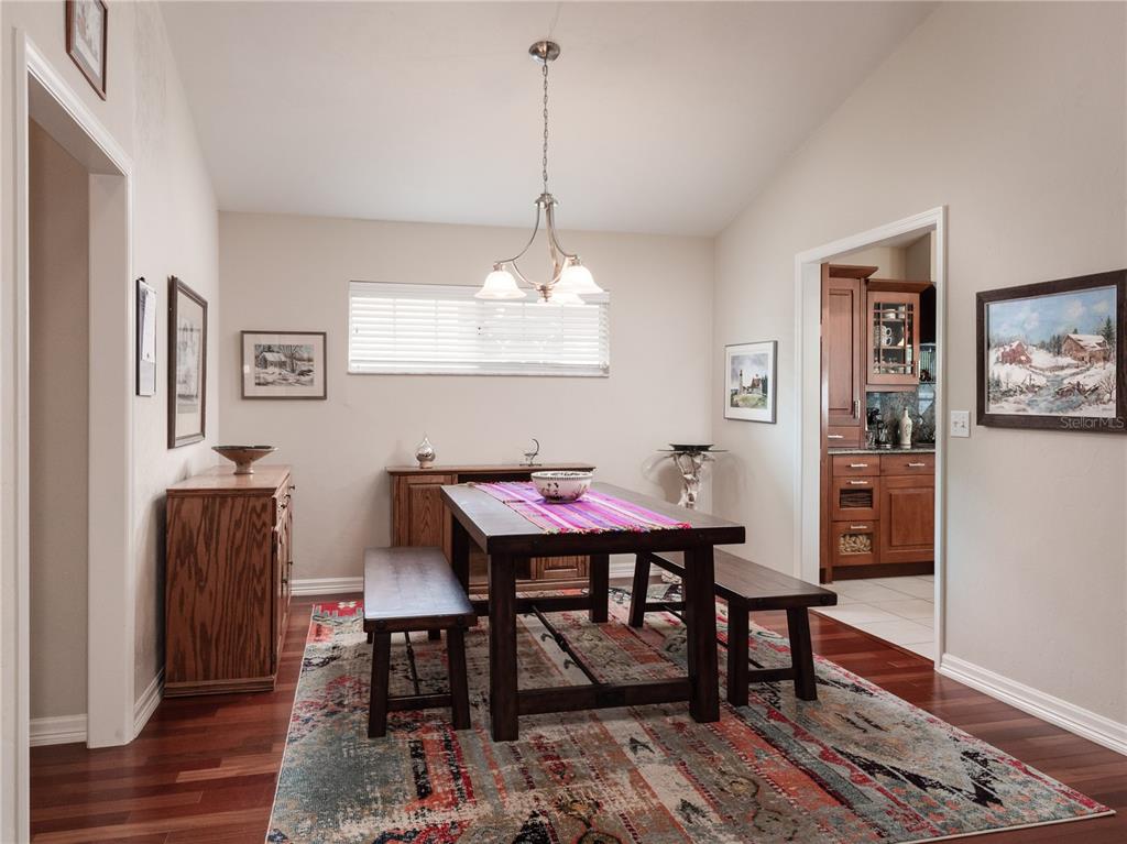 A dining room features a wooden table with two benches, a patterned rug, and hardwood floors — 6126 NW 36TH DRIVE, GAINESVILLE, FL