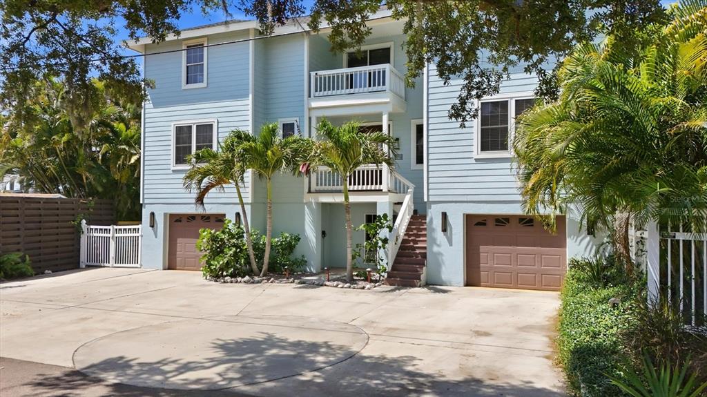 A three-story light blue house with two garages and a concrete driveway — 5544 DINAH LANE, SARASOTA, FL