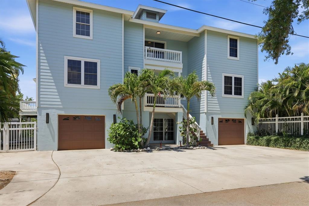 A three-story light blue house with two garage doors and a central balcony — 5544 DINAH LANE, SARASOTA, FL