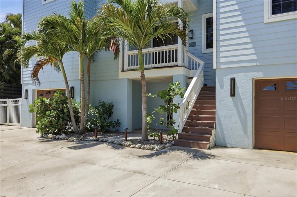 A light blue house with a brown garage door, palm trees, and wooden stairs — 5544 DINAH LANE, SARASOTA, FL