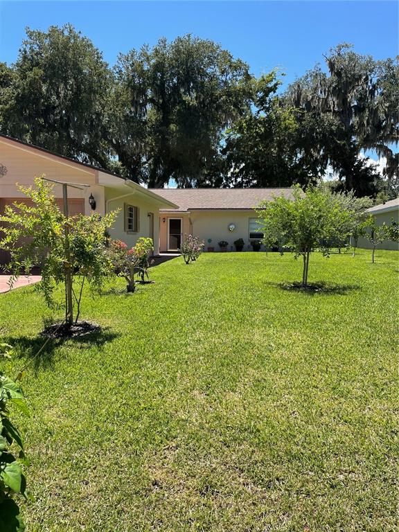 A single-story house with a light-colored exterior sits behind a large, grassy front yard — 12 FARRADAY LANE UNIT A, PALM COAST, FL