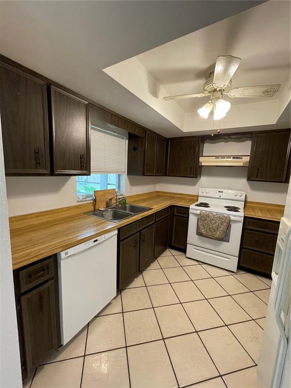 A kitchen features dark wood cabinets, light wood countertops, white appliances, and a ceiling fan — 12 FARRADAY LANE UNIT A, PALM COAST, FL