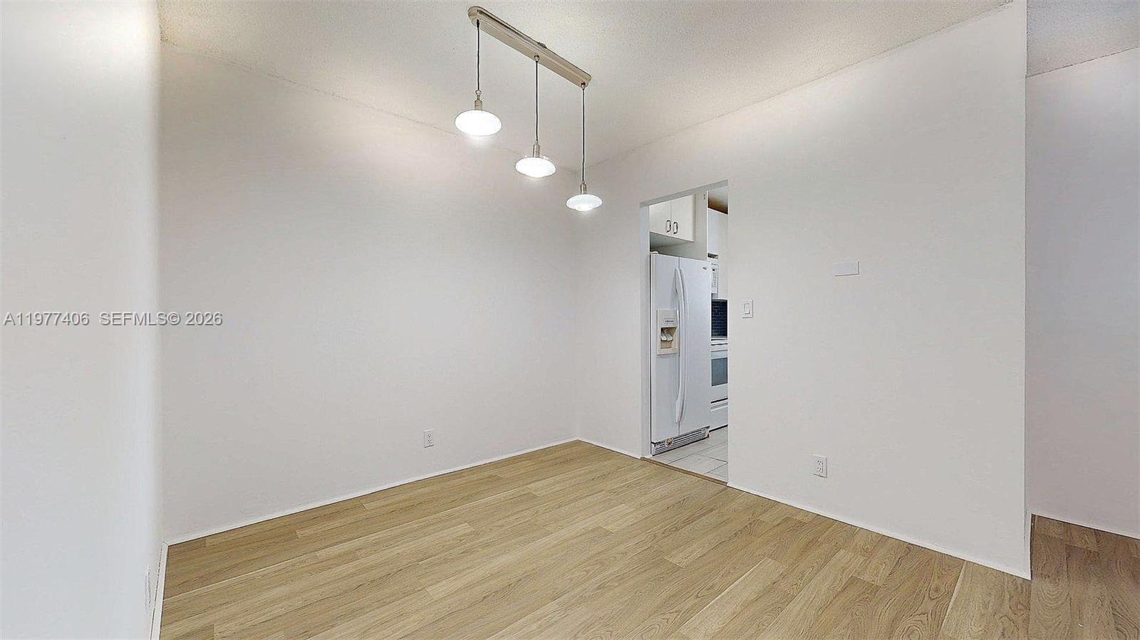 A dining area features light wood-look flooring, white walls, and a three-light pendant fixture — 5300 Washington St # D303, Hollywood FL 33021, HOLLYWOOD, FL