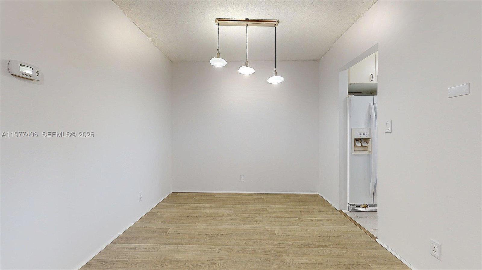 A dining area features light wood-look flooring, white walls, and a three-light pendant fixture — 5300 Washington St # D303, Hollywood FL 33021, HOLLYWOOD, FL