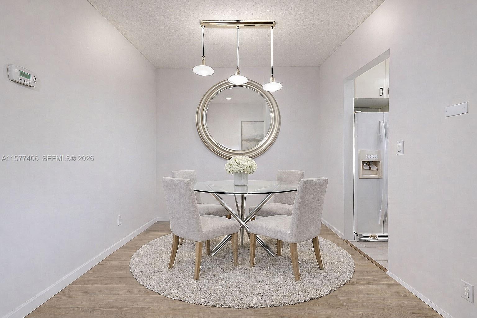 A dining area features a glass-topped table, four upholstered chairs, and a circular wall mirror — 5300 Washington St # D303, Hollywood FL 33021, HOLLYWOOD, FL