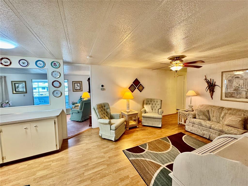 A living room features light wood flooring, a patterned area rug, and two armchairs — 5511 DENMARK DRIVE, BRADENTON, FL
