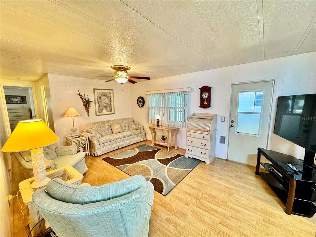 A living room features light wood flooring, a patterned area rug, and a ceiling fan — 5511 DENMARK DRIVE, BRADENTON, FL