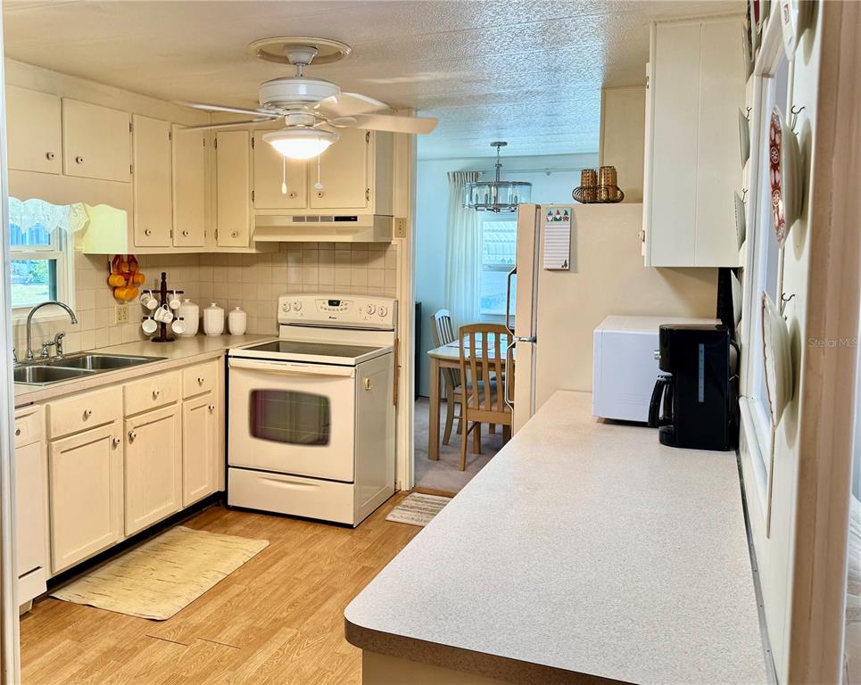 A kitchen with white cabinets, light countertops, and a dining area visible in the background — 5511 DENMARK DRIVE, BRADENTON, FL