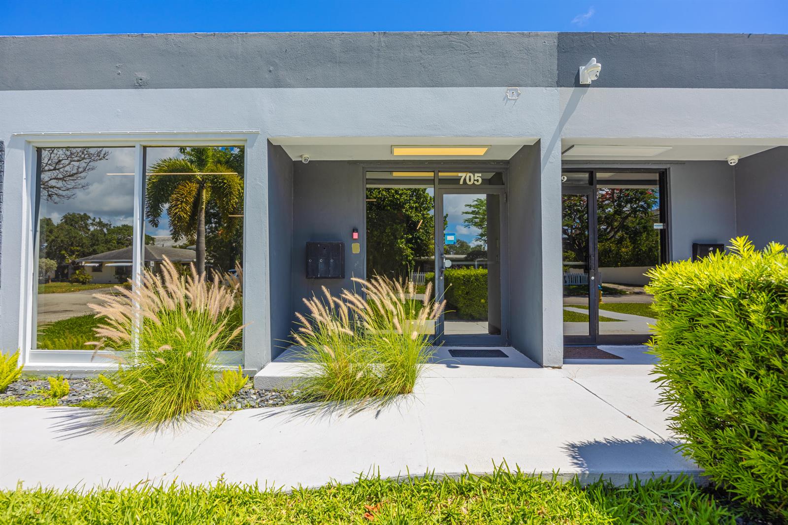 The exterior of a commercial building features a glass entrance door labeled 705 — 705 Bond Way, Delray Beach FL 33483, DELRAY BEACH, FL