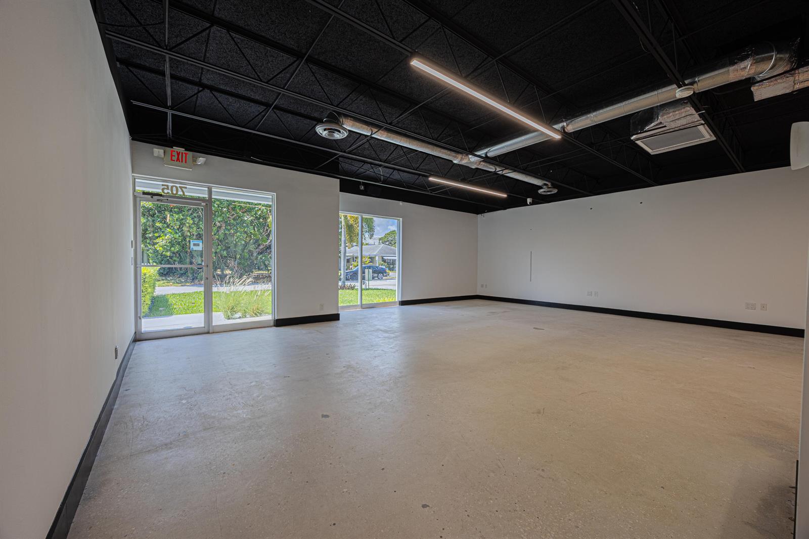 An empty commercial space features a black drop ceiling, concrete floors, and large glass windows — 705 Bond Way, Delray Beach FL 33483, DELRAY BEACH, FL