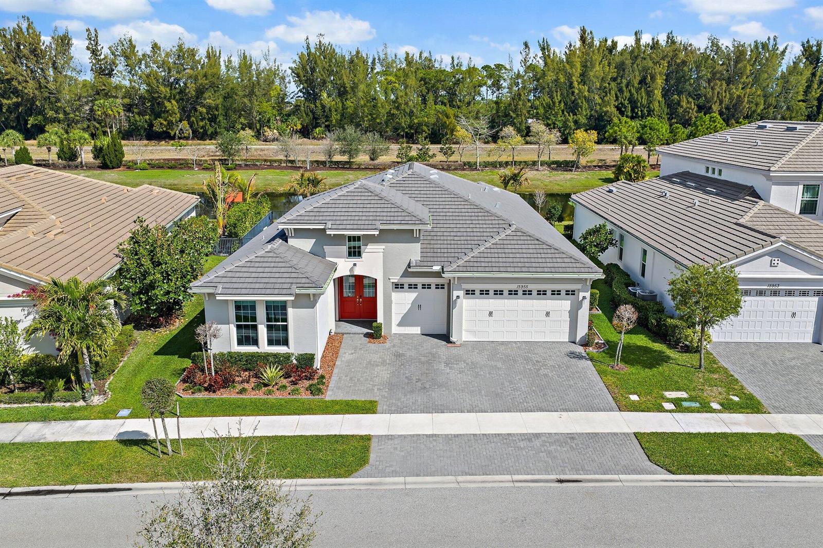 An aerial view of a single-story suburban house with a gray tile roof and driveway — 15955 Whippoorwill Circle, Westlake FL 33470, WESTLAKE, FL
