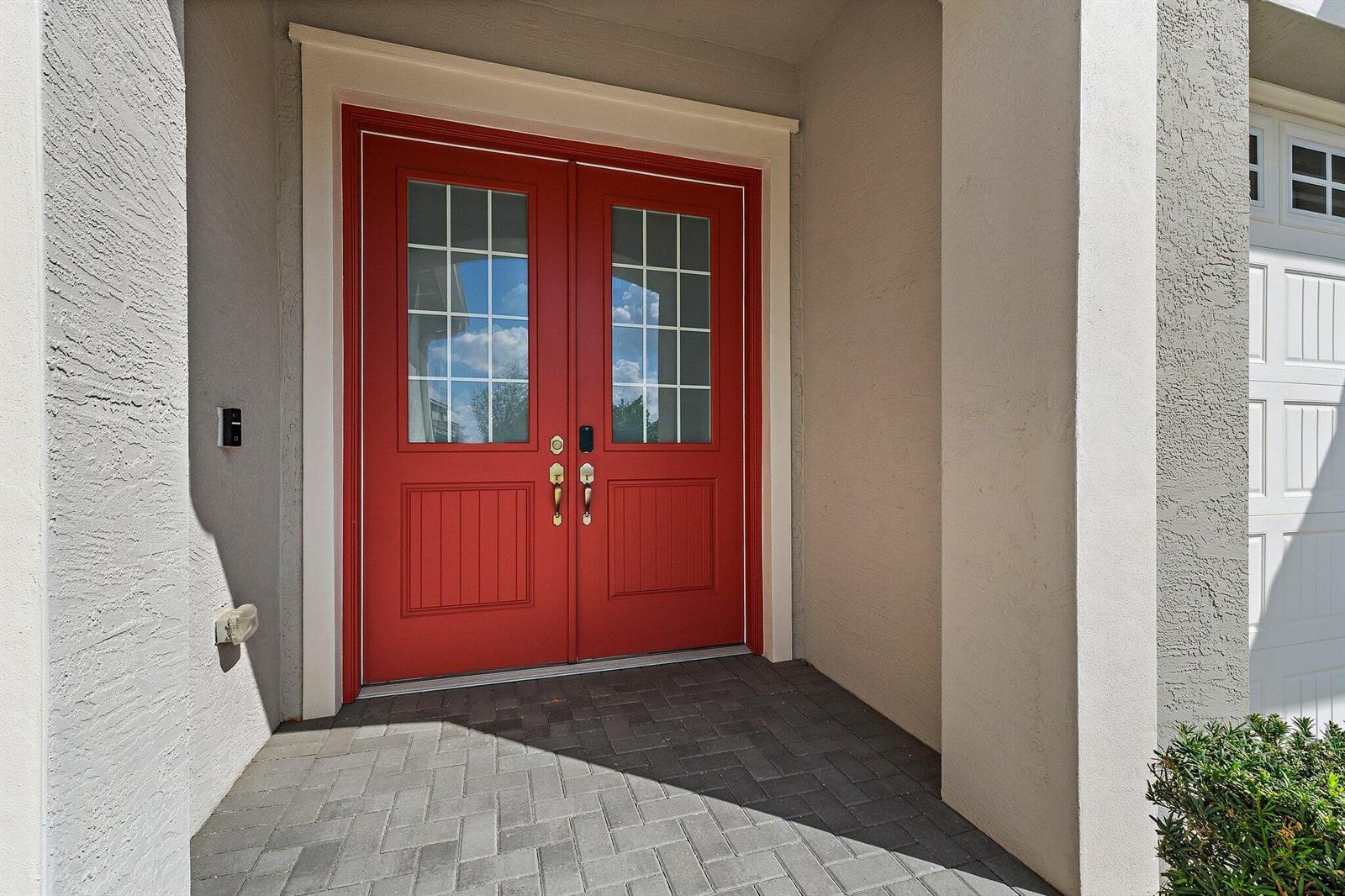 A red double front door with glass panes is set within a covered entryway — 15955 Whippoorwill Circle, Westlake FL 33470, WESTLAKE, FL