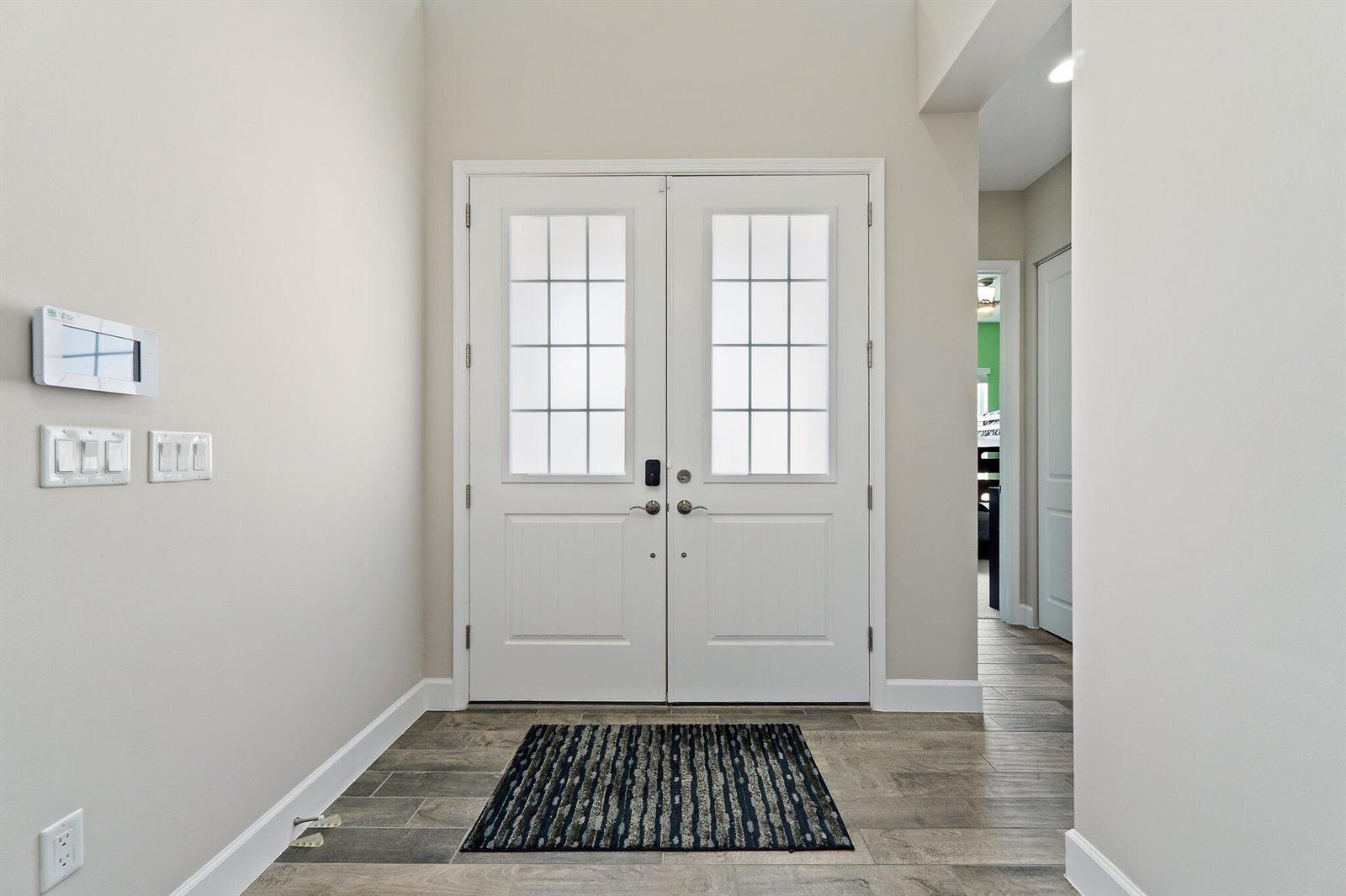 An entryway features double white doors, light-colored walls, and wood-look tile flooring — 15955 Whippoorwill Circle, Westlake FL 33470, WESTLAKE, FL