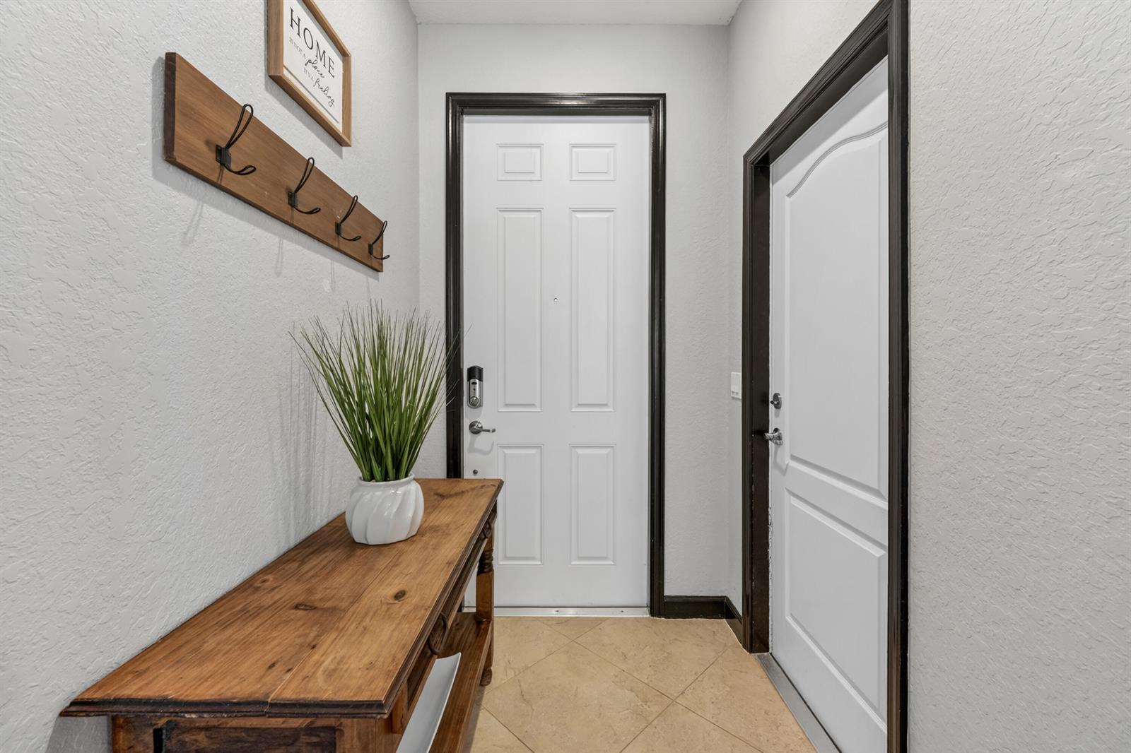 An entryway features a wooden console table, coat rack, and two white doors with dark trim — 3051 SW Otter Lane, Stuart FL 34997, STUART, FL