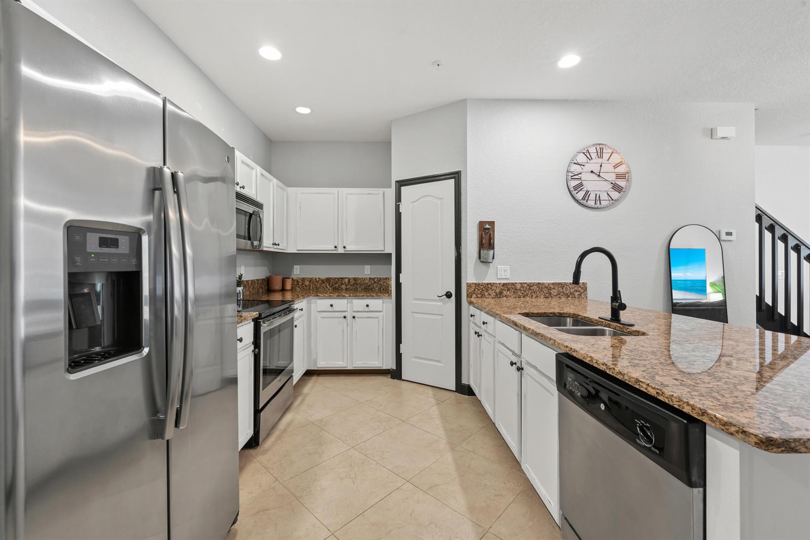 A kitchen features white cabinets, granite countertops, stainless steel appliances, and a large wall clock — 3051 SW Otter Lane, Stuart FL 34997, STUART, FL