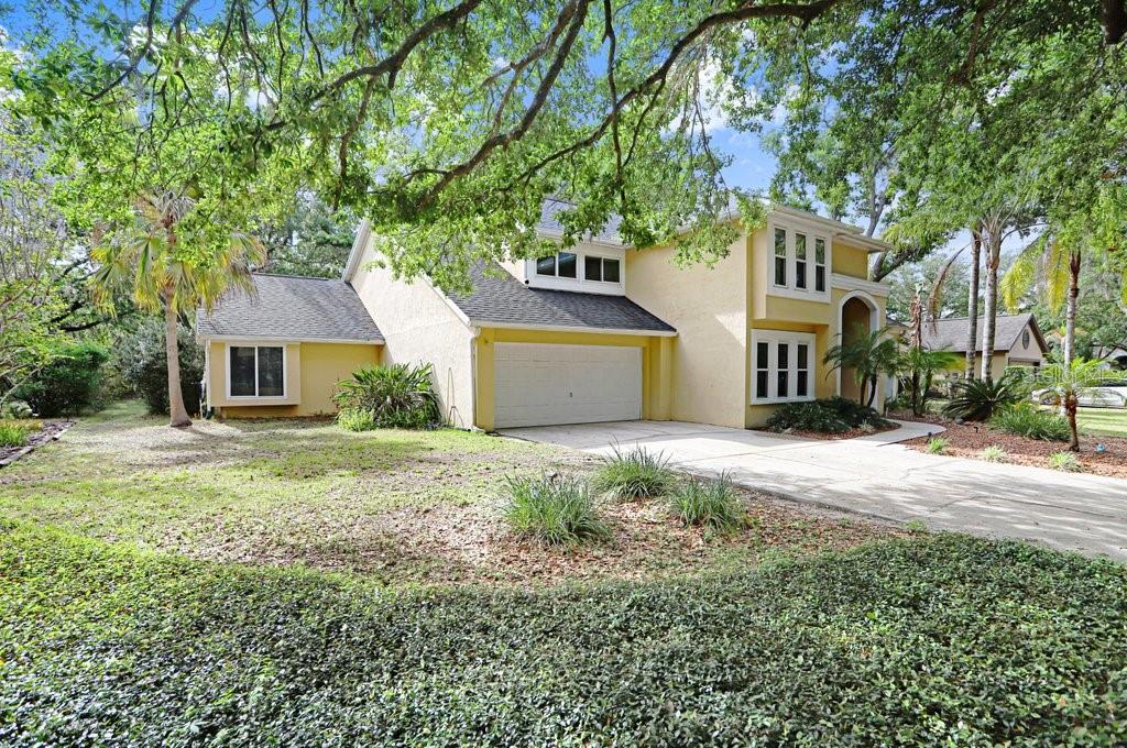 A two-story yellow house with a two-car garage and mature trees in the front yard — 6214 FARTHING STREET, TAMPA, FL