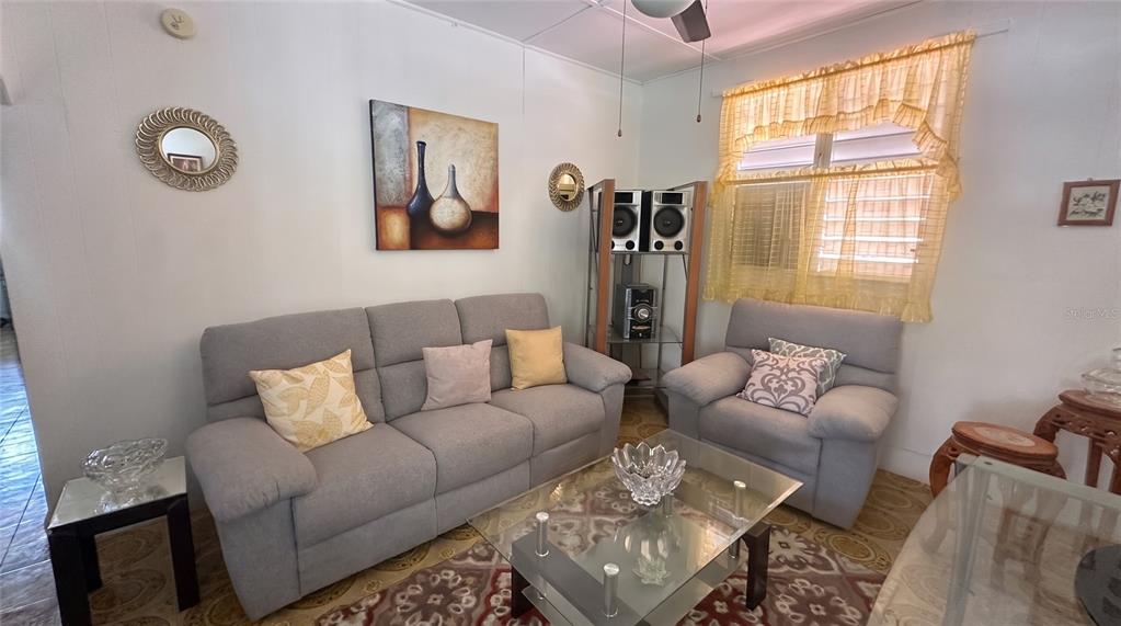 A living room features a gray sofa and armchair, a glass coffee table, and wall art — calle 5 COMUNIDAD RURAL VILLA BORINQUEN, CANOVANAS, PR