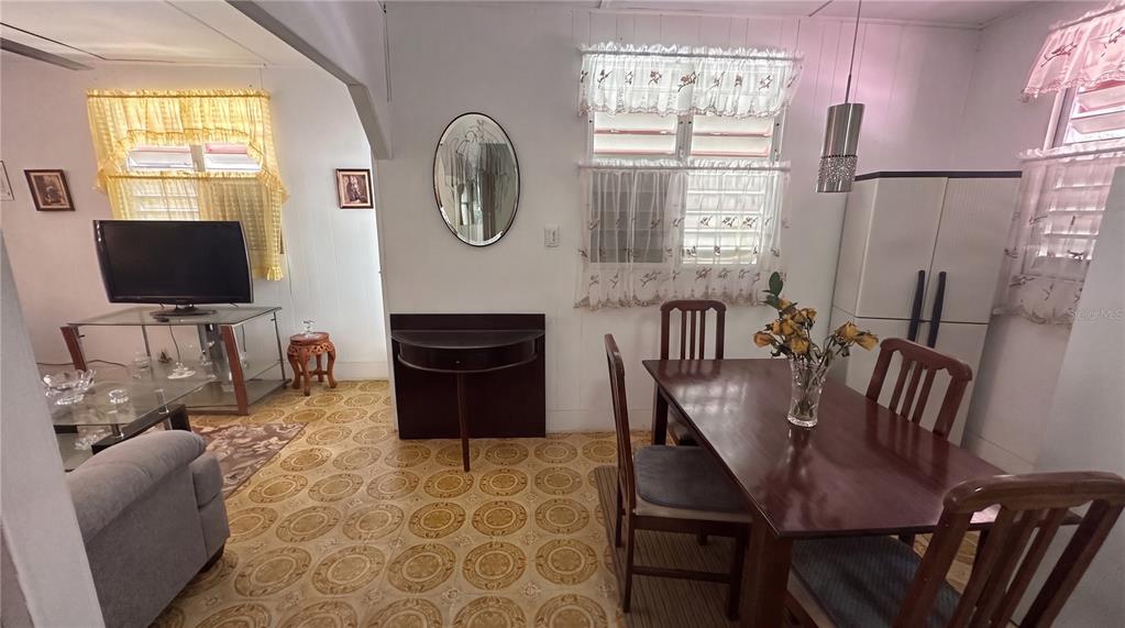 A dining area with patterned tile flooring, a wooden table, and a wall-mounted oval mirror — calle 5 COMUNIDAD RURAL VILLA BORINQUEN, CANOVANAS, PR