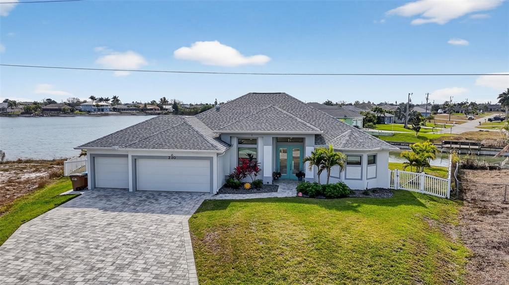 A single-story house with a gray roof, white garage doors, and a paved driveway — 230 NE 18TH STREET, CAPE CORAL, FL