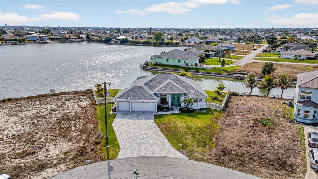 An aerial view of a single-story house with a paved driveway situated on a waterfront lot — 230 NE 18TH STREET, CAPE CORAL, FL